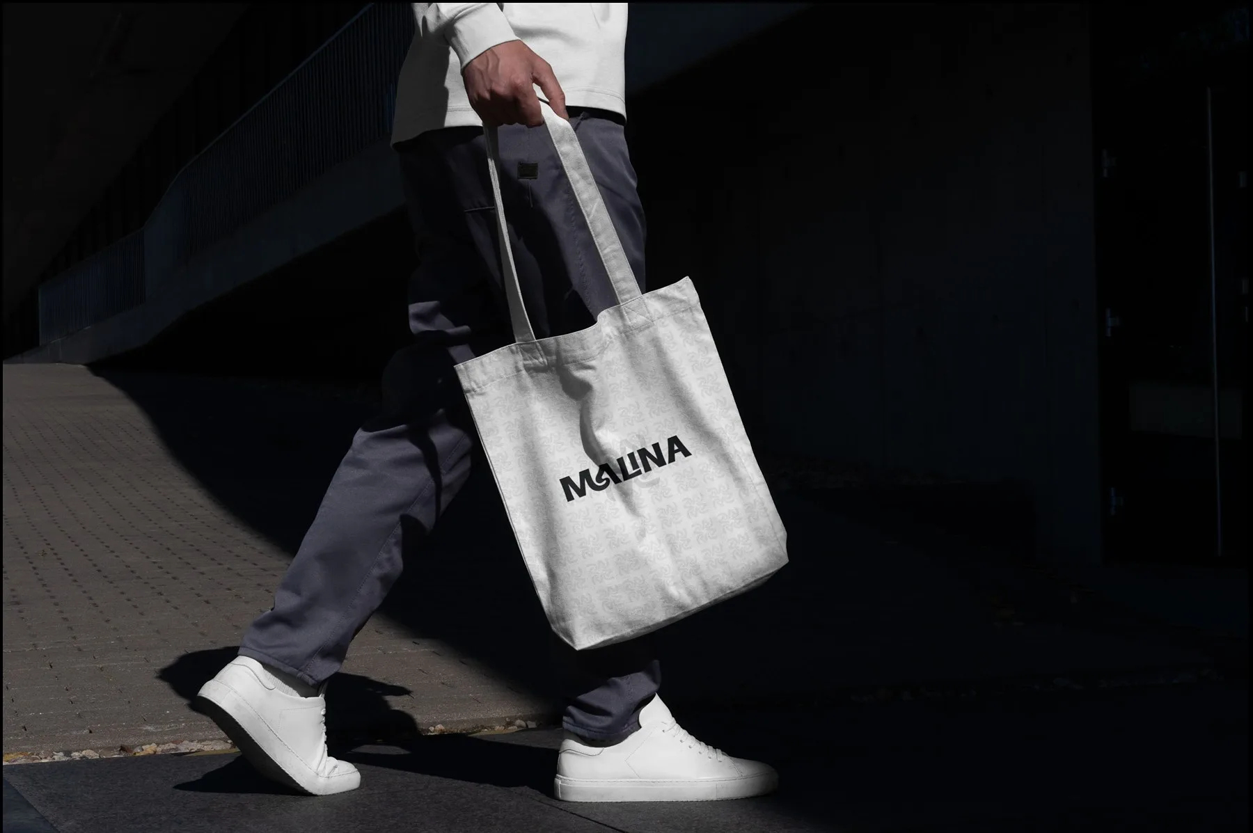 Malina tote bag carried past a building on a sunlit pavement